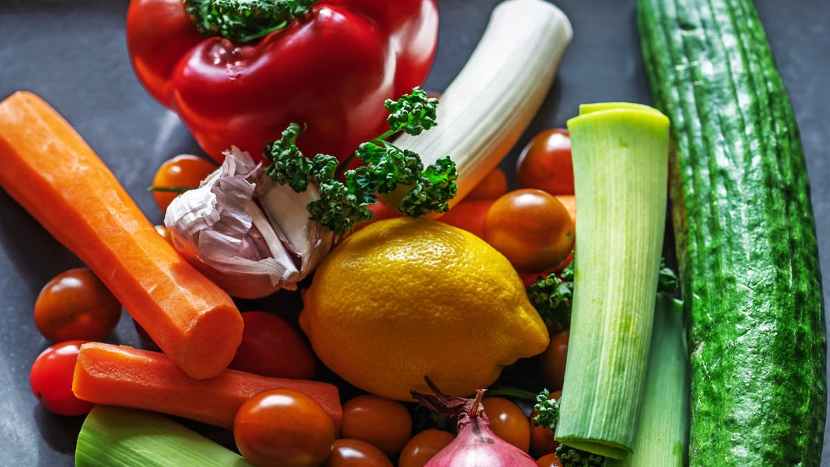 A vibrant flat lay of fresh vegetables and ingredients including peppers, leeks, and lemon.